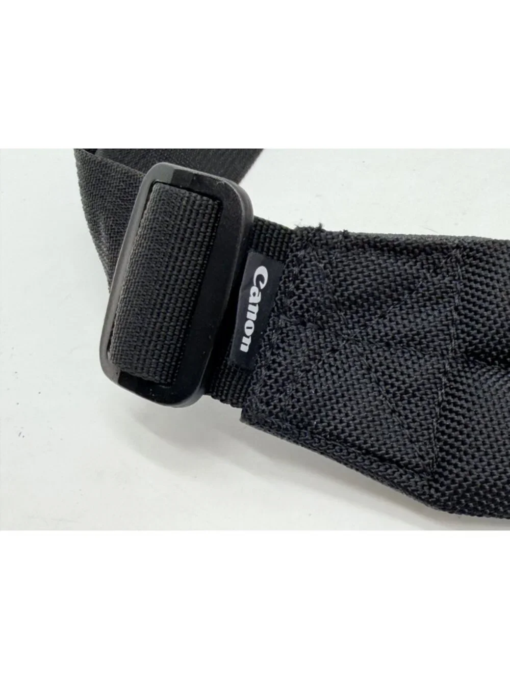 black Canon padded camera shoulder strap featuring an adjustable nylon web belt